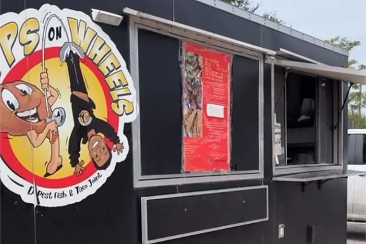 The black Sipps On Wheels food truck with its round cartoon logo, red menu board and service window